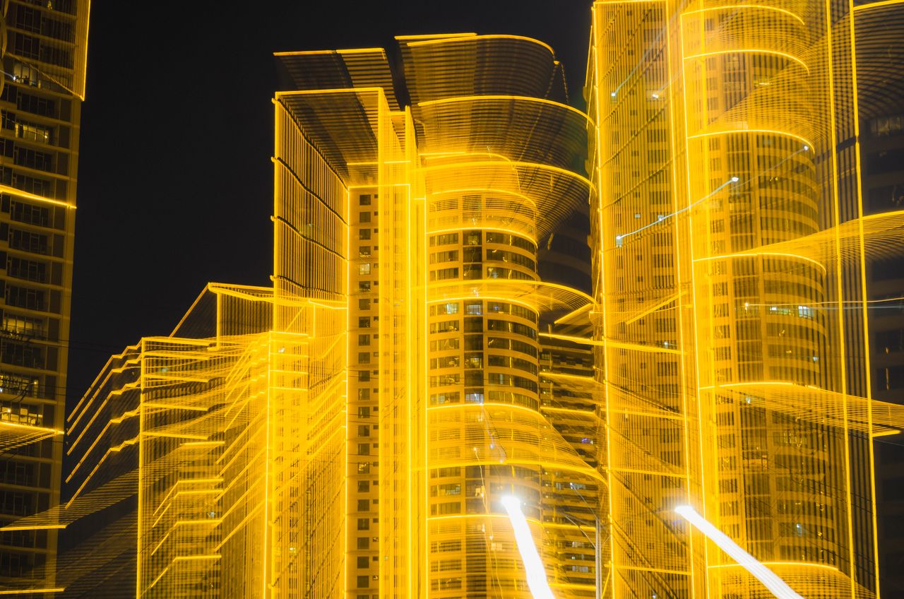 Vibrant abstract long exposure of city skyscrapers with glowing lights at night.