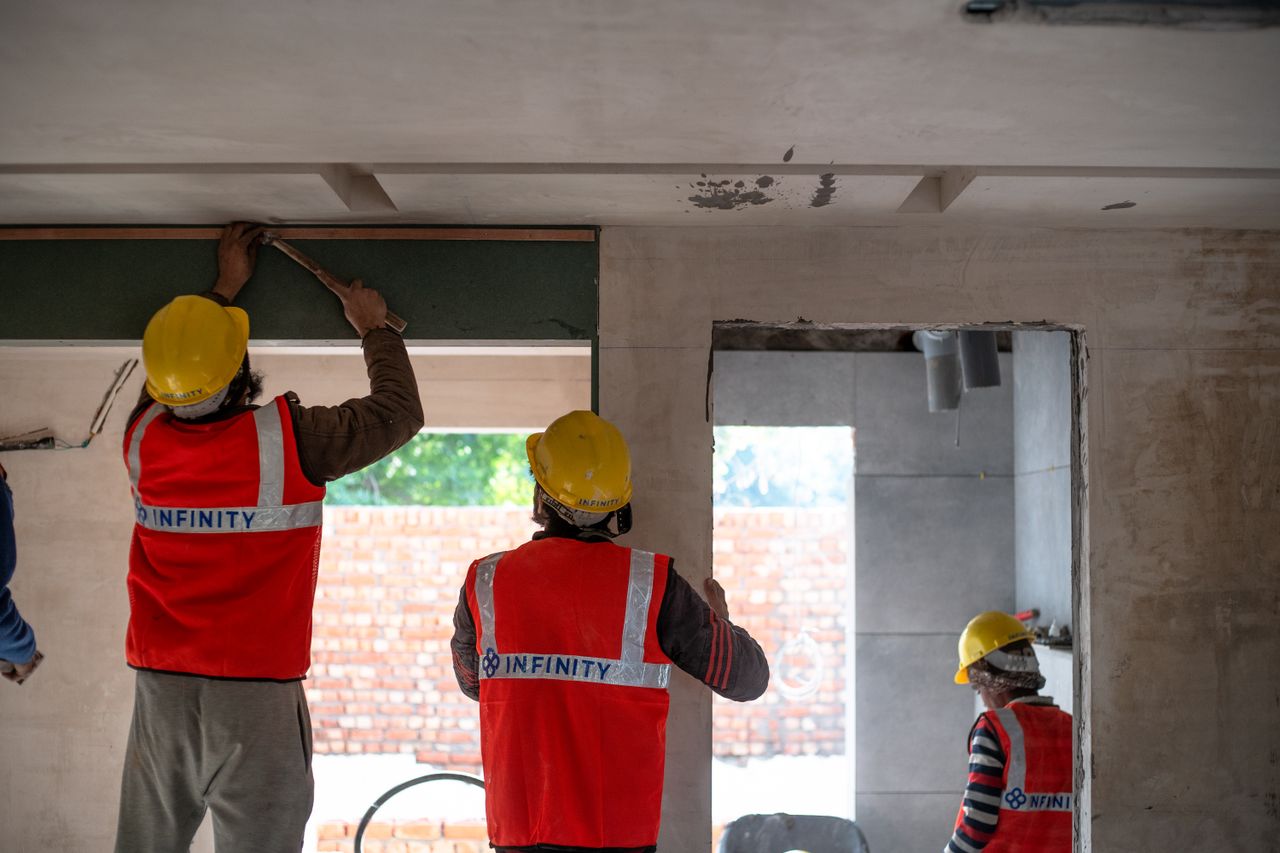 creative-approach-img Construction workers renovating interior space in Delhi with safety gear and tools.