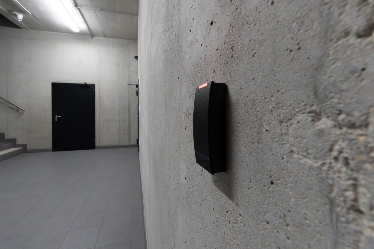 programs-03 A smart electronic access terminal mounted on a concrete wall in an industrial interior for enhanced security.