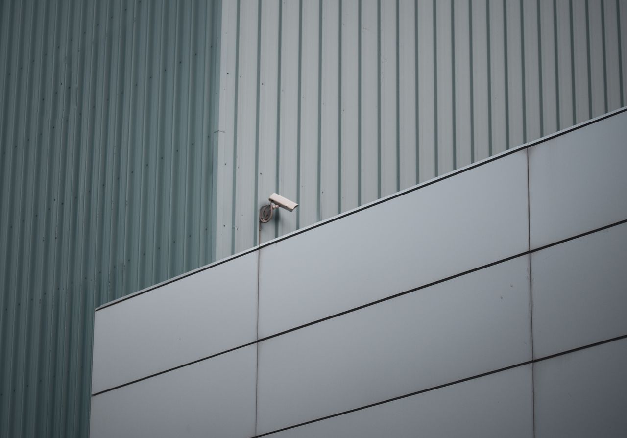 Security camera on modern building facade, highlighting urban safety and surveillance.
